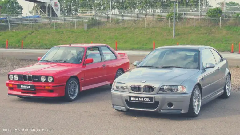 A red BMW E30 M3, and a gray BMW E46 M3 CSL